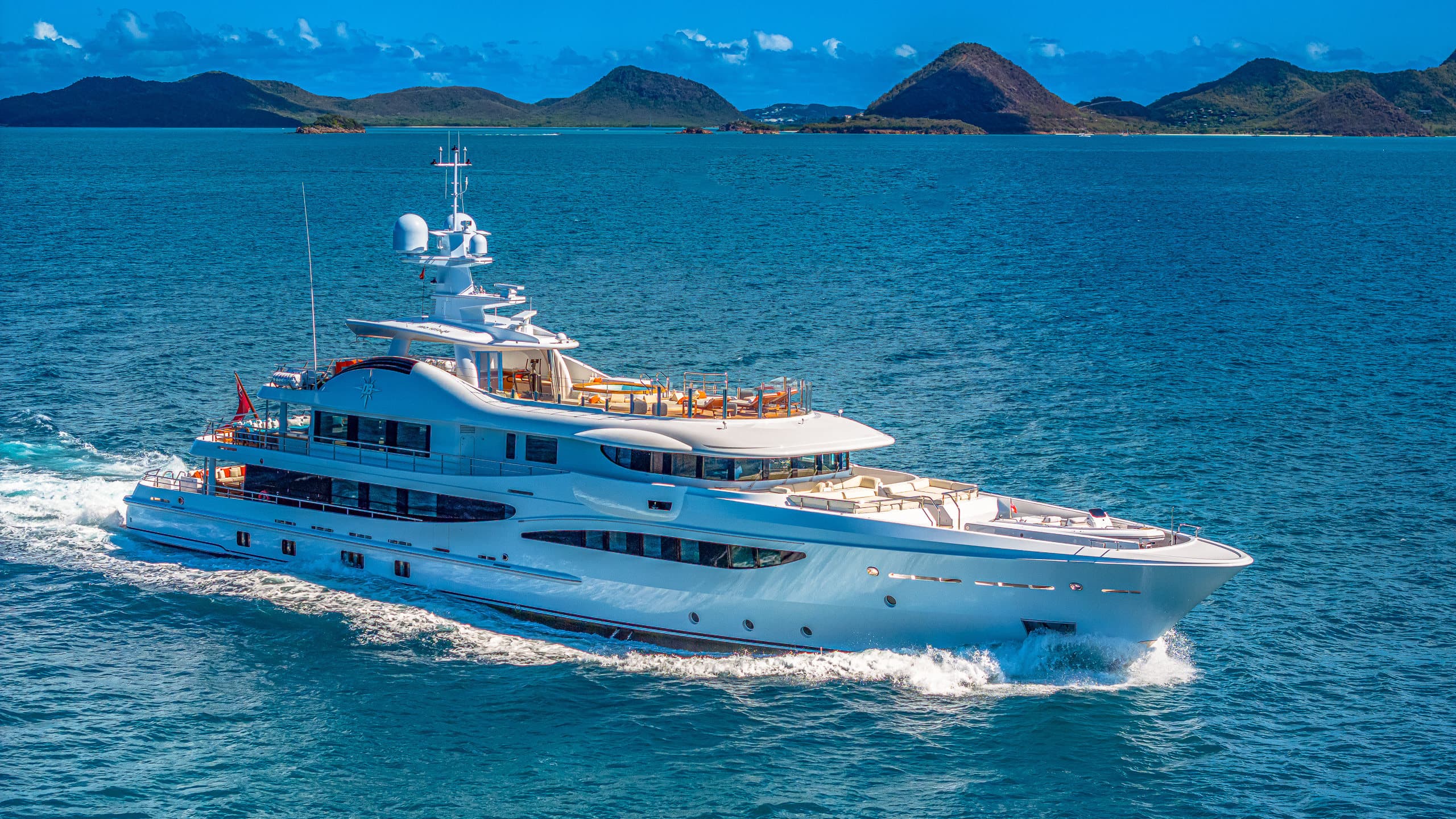 Deep Blue superyacht cruising off a tropical coastline